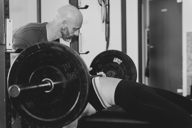 Coach e atleta alla panca con bilanciere